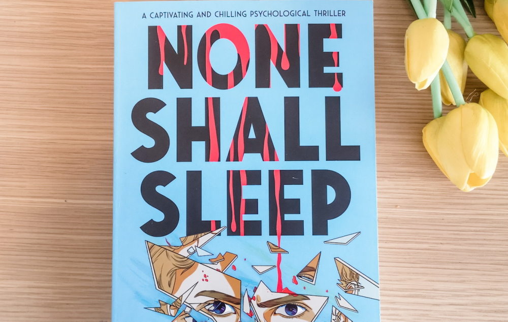 None Shall Sleep book with flowers on table